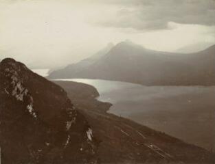 [Vue sur le lac, Veyrier-du-Lac, Menthon-Saint-Bernard, le Roc de Chère, le bout-du-lac et le massif des Bauges à partir du sommet du Mont-Veyrier] / [non identifié]. 1910
