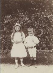 [Fillette et petit garçon tenant une baguette de bois devant un massif de fleurs] / [non identifié]. [s.n.], [Entre 1908 et 1909]. [1908]-[1909]