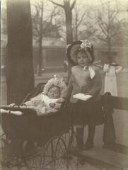 1 vue [Bébé dans son landau à coté d'une fillette debout sur un banc] / [non identifié].